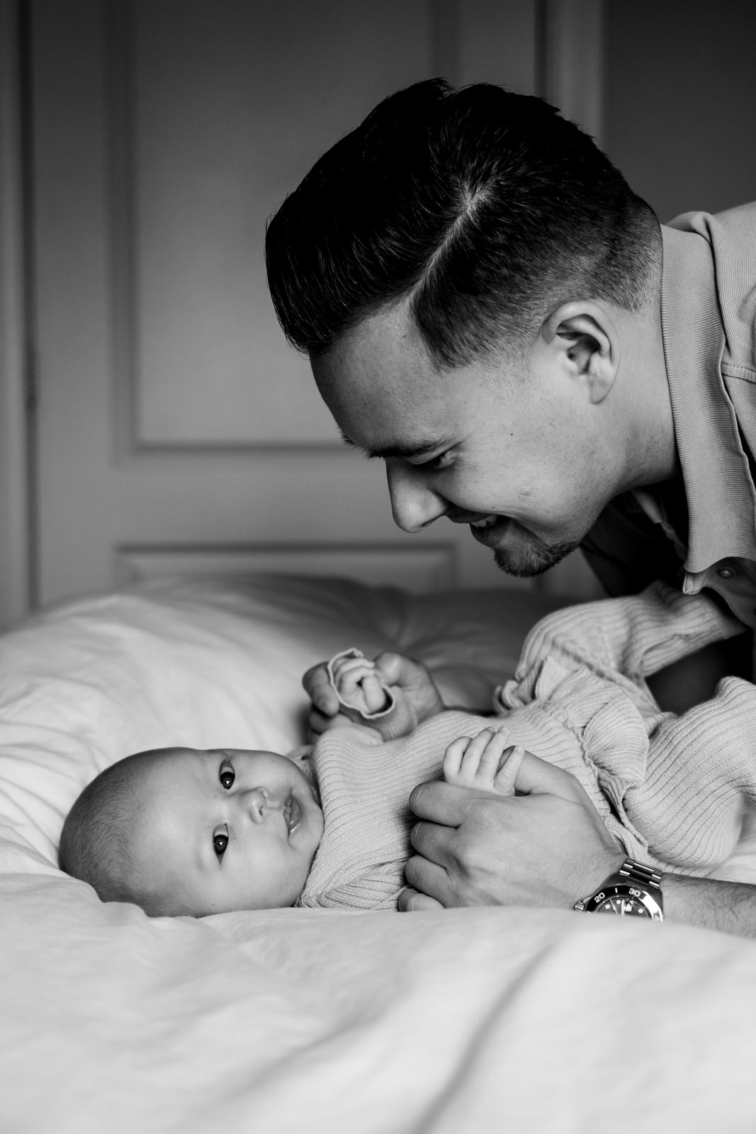 Papa ligt op het bed met zijn dochter, terwijl zij wakker is en om zich heen kijkt.