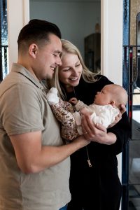 Trotse ouders kijken blij naar hun dochter terwijl ze haar dicht tegen zich aan houden.