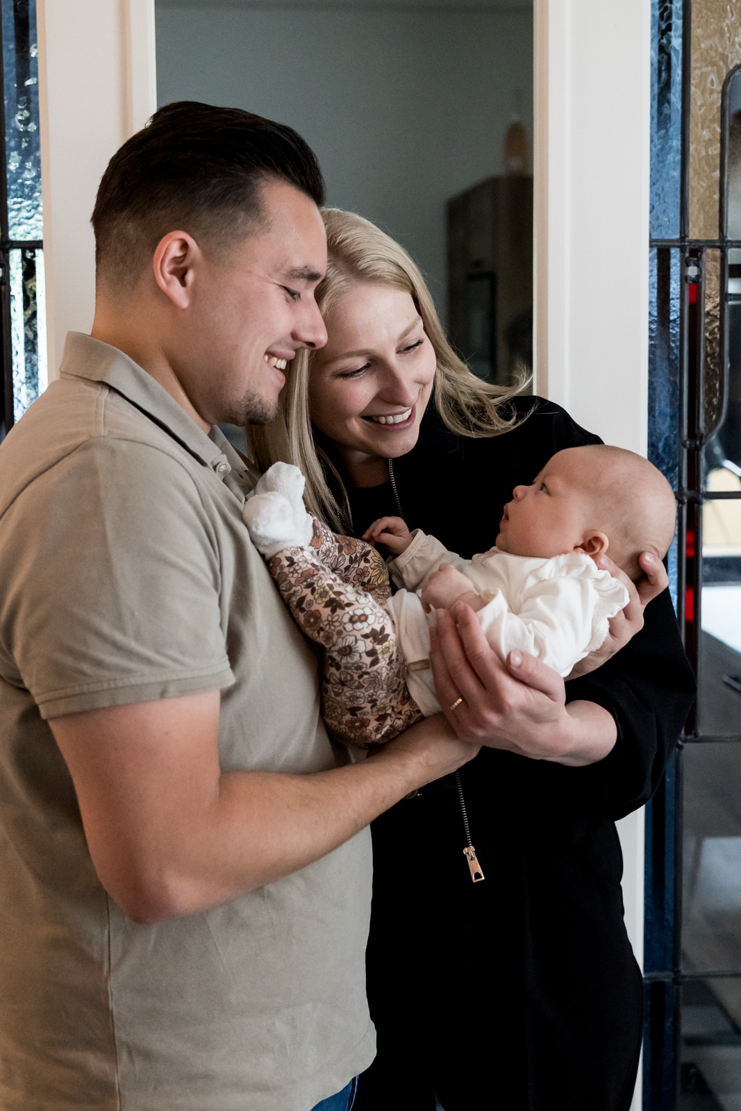 Trotse ouders kijken blij naar hun dochter terwijl ze haar dicht tegen zich aan houden.