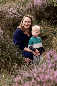 Mama en zoon tussen de heide op Het Leesten in Ugchelen, kijkend naar papa, terwijl mama haar zoon vasthoudt met een warme glimlach.