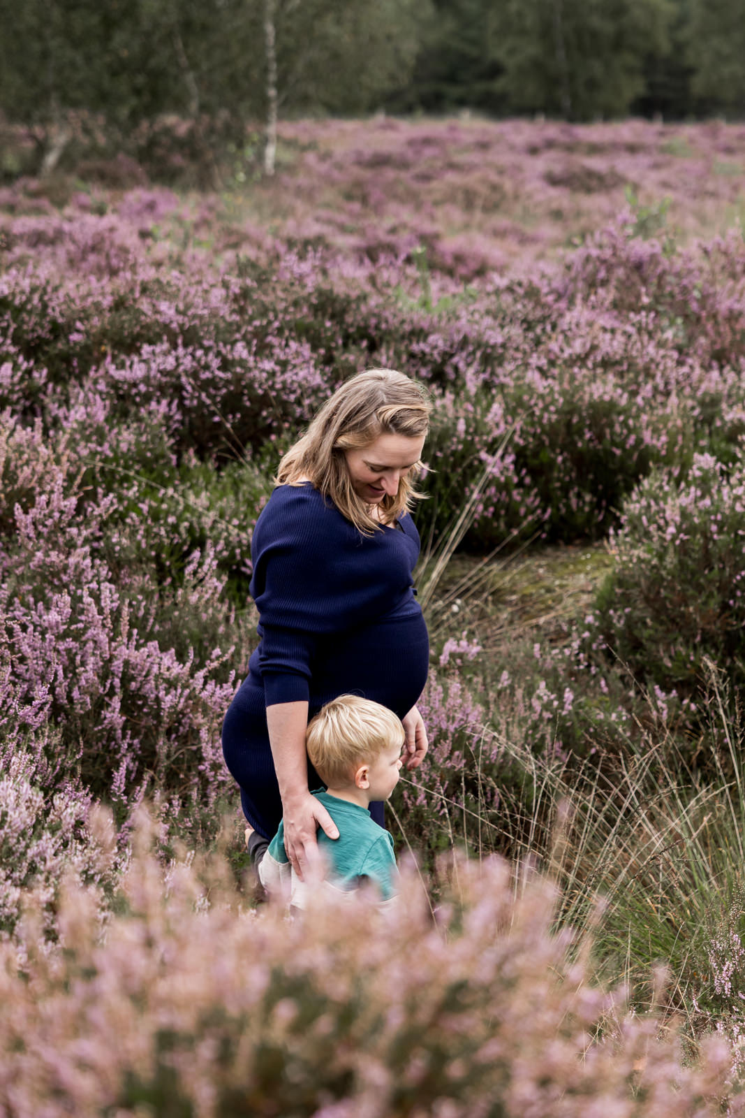 Mama loopt met haar zoon door de heide op Het Leesten in Ugchelen, met een hand op zijn rug en een liefdevolle blik naar hem.