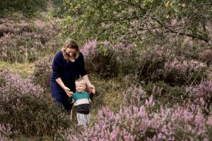 Mama en haar zoon wandelen door de paarse heide tijdens een zwangerschapsreportage op Het Leesten in Ugchelen, genietend van de natuur.